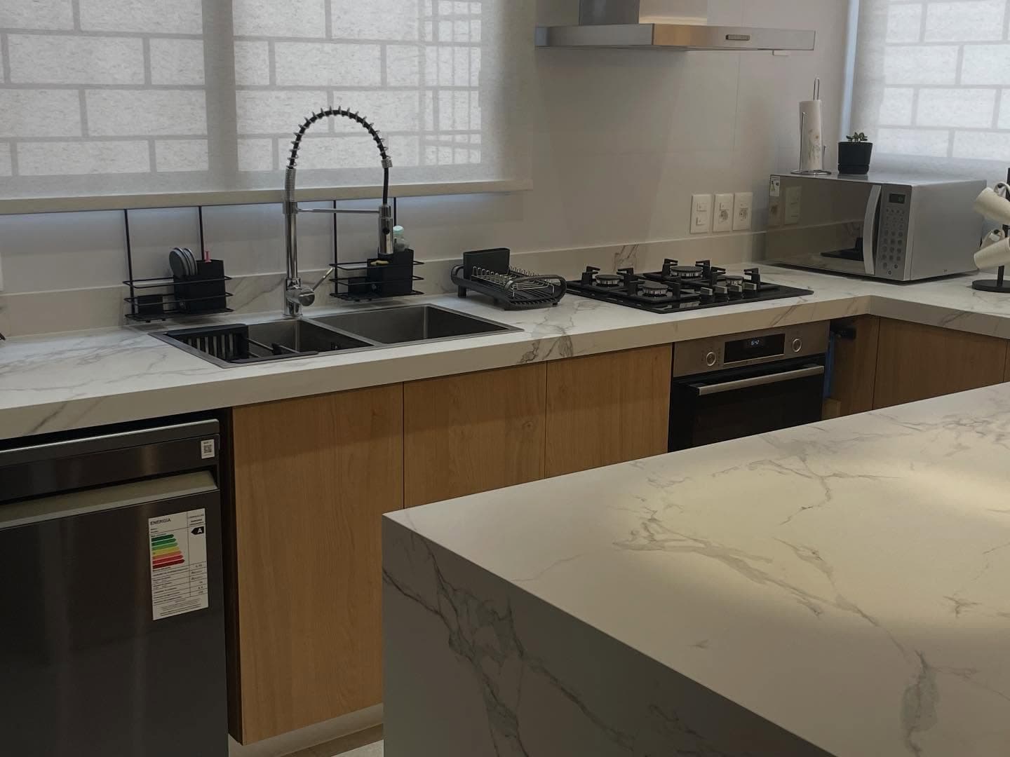 Cocina con isla y mesada en cascada en Dekton Aura — Montevideo · Nuevo Horizonte Marmolería