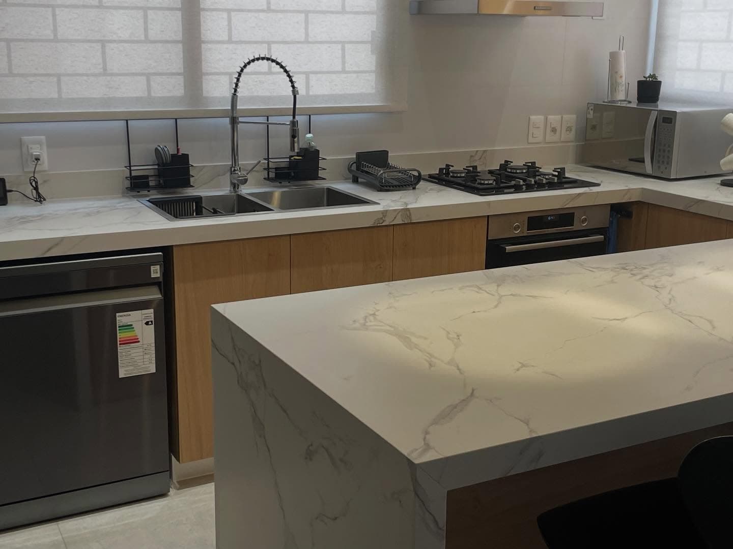 Cocina con isla y mesada en cascada en Dekton Aura — Montevideo · Nuevo Horizonte Marmolería